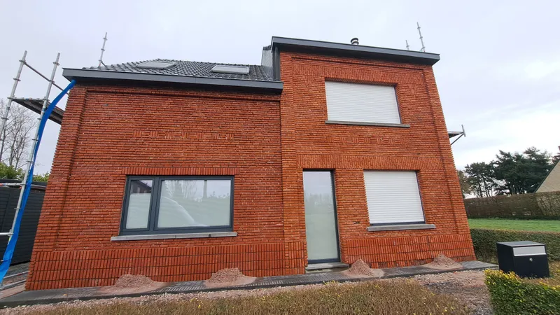 Voor de gevelrenovatie in Heist-op-den-Berg, met uitgesleten voegen en vervuilde bakstenen gevel.